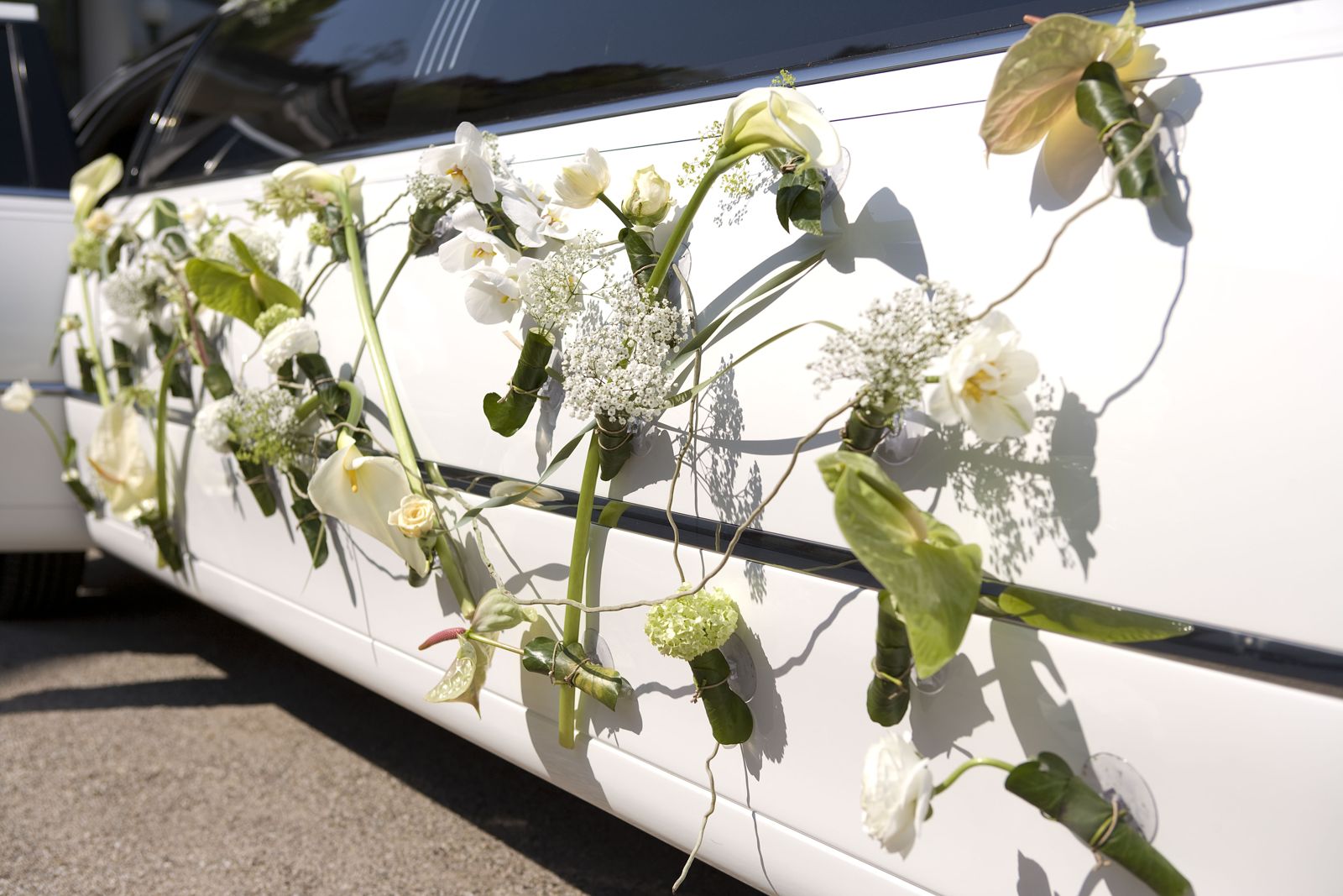 Blumenschmuck aus Anthurien und Ranunkeln an einem weißen Fahrzeug